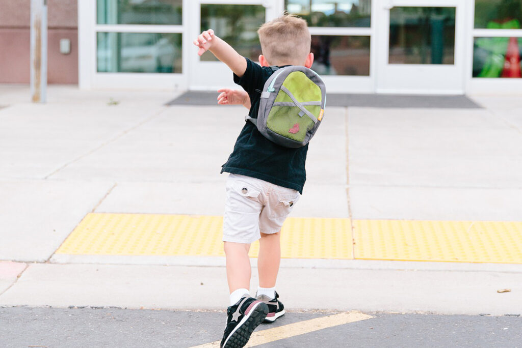 Ett skolbarn som springer in i skolan.