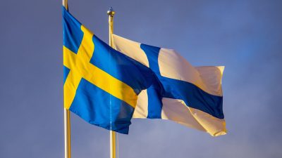 En svensk och en finsk flagga bredvid varandra utomhus.