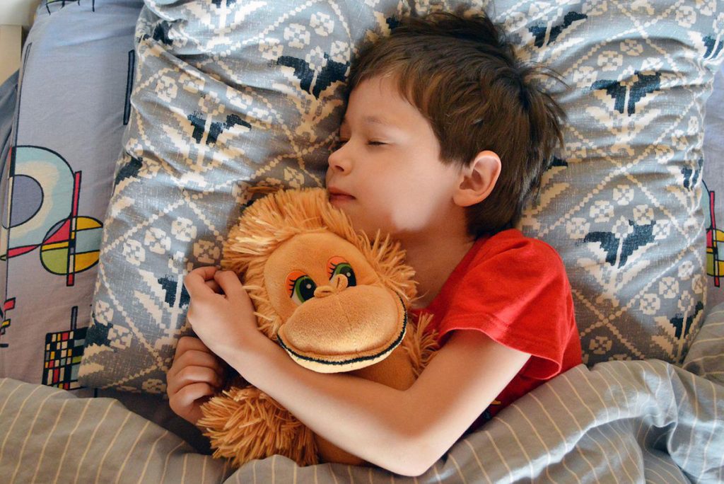 Ett barn som sover och kramar ett apkramdjur.