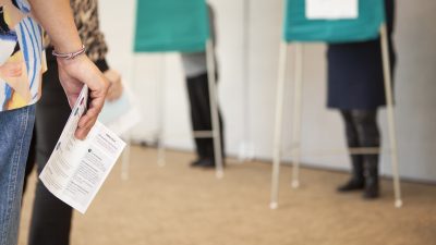 Människor röstar bakom valskärmar.